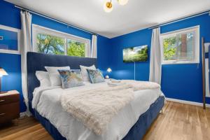 ein blaues Schlafzimmer mit einem großen Bett mit blauen Wänden in der Unterkunft Xcape to a Tranquil 4 Bedroom Retreat in Alexandria