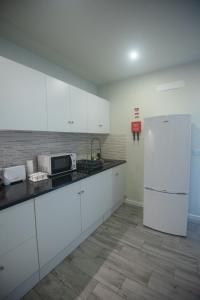 eine Küche mit weißen Schränken und einem weißen Kühlschrank in der Unterkunft Vista do Baixio in Vila Franca do Campo + 3 Fotos