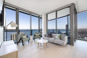 a living room with a couch and chairs and windows at ULTIQA Signature at Broadbeach in Gold Coast