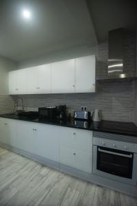 eine Küche mit weißen Schränken und einem Herd mit Backofen in der Unterkunft Vista do Tagarete in Vila Franca do Campo