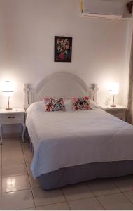 1 dormitorio con 1 cama blanca con 2 mesas y 2 lámparas en Iluminada y confortable habitaciones en Casa Margarita Oaxaca en Oaxaca de Juárez