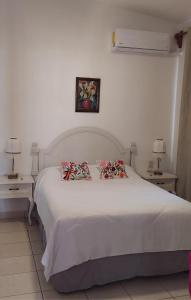a bedroom with a white bed with two tables and two lamps at Iluminada y confortable habitaciones en Casa Margarita Oaxaca in Oaxaca City