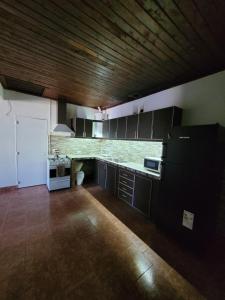 a kitchen with black cabinets and a wooden ceiling at Departamento Castello in El Bolsón