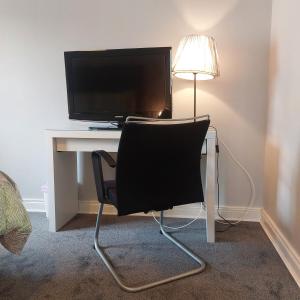 a chair in front of a desk with a television at Lawnbrook Town House in Belfast