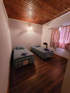 two beds in a room with wooden floors at Departamento Castello in El Bolsón
