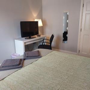 a bedroom with a bed with a desk and a television at Lawnbrook Town House in Belfast