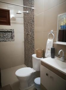 ein weißes Badezimmer mit Toilette und Waschbecken in der Unterkunft Casa de Praia Toca da Onça in São Miguel do Gostoso