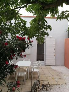 een patio met een tafel, 2 stoelen en rozen bij Villa au Calme avec Extérieur et parking gratuit aux portes d'Aix et Marseille Emplacement idéal in Marseille