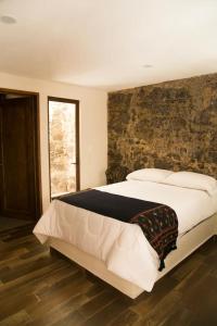 ein Schlafzimmer mit einem großen Bett und einer Steinmauer in der Unterkunft El Ciruelo in Teziutlán