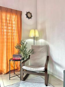 a chair and a table with a lamp and a clock at Nawwarah Homes @ Southville City (WiFi + NETFLIX) in Kajang