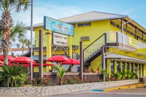 a restaurant with red umbrellas in front of a yellow building at Driftwood Dreams in Panama City Beach