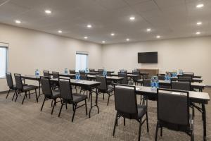 una sala de conferencias con mesas, sillas y una pantalla en Candlewood Suites Deer Park, an IHG Hotel en Deer Park