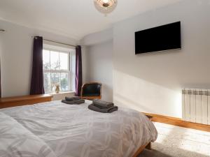 a bedroom with a bed with a television and a chair at Wether Fell View in Hawes