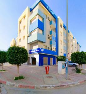 un edificio azul y blanco con árboles delante en Coquette Appartement, en Boumhel El Bassatine