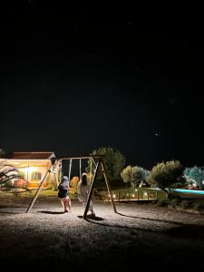 two children playing on a swing set at night at Monte das Hortas Velhas in Viana do Alentejo