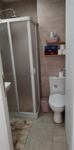 een badkamer met een douche en een wit toilet bij Coquette Appartement in Boumhel El Bassatine