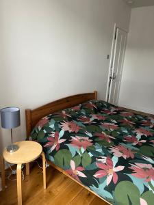 a bedroom with a bed with a floral bedspread and a table at Ilford Hidden Gem in Ilford