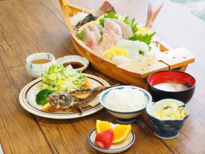 uma mesa com um prato de comida e um barco de comida em Shodoshima Olive Youth Hostel em Shodoshima