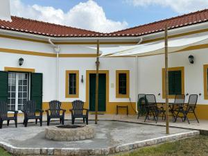 een patio met stoelen en een vuurplaats voor een huis bij Monte das Hortas Velhas in Viana do Alentejo