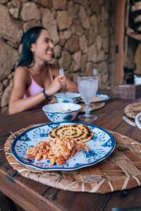 a woman sitting at a table with a plate of food at Las Dunas Beach Guest House in Juan de Acosta