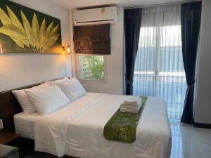 a bedroom with a bed with white sheets and a window at Lemon Guesthouse in Chiang Mai