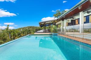 a swimming pool in front of a house at Kokomo in Airlie Beach