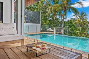a living room with a swimming pool and a table at Kokomo in Airlie Beach