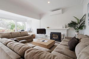 sala de estar con sofá y chimenea en In the Heart of Flinders - A Beachside Family Escape, en Flinders