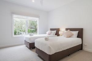 2 camas en una habitación blanca con ventana en In the Heart of Flinders - A Beachside Family Escape, en Flinders