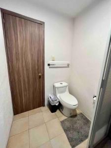 ein Badezimmer mit einem WC und einer Holztür in der Unterkunft Oasis 101 in El Gallinero