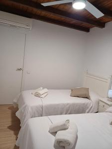 2 posti letto in una camera bianca con asciugamani di La casita Ronda a Ronda