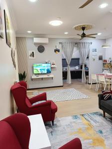 Il comprend un salon doté de fauteuils rouges et d'une télévision à écran plat. dans l'établissement DH Merlimau Homestay, à Merlimau