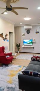 een woonkamer met een tv en een rode bank bij DH Merlimau Homestay in Merlimau