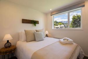 a bedroom with a large white bed with a window at Hillside Villa 3- Walk To Town- AC- Free Parking in Queenstown