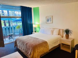 Habitación de hotel con cama y ventana grande en Foghorn Harbor Inn, en Los Ángeles