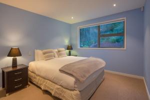 een slaapkamer met een bed en een raam bij Aurora Lodge- AC- Free Parking- Hot Tub- BBQ in Queenstown