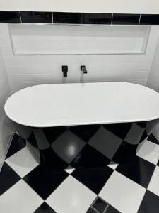 een wit bad in een badkamer met een zwart-witte vloer bij Rare Broulee beachfront house in Broulee