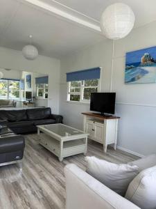 een woonkamer met een bank en een tv bij Rare Broulee beachfront house in Broulee