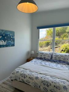 een slaapkamer met een bed en een groot raam bij Rare Broulee beachfront house in Broulee
