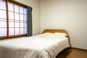 a white bed in a room with a window at White Lodge Fukujuso in Iiyama