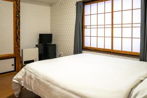 a bedroom with a bed and a window at White Lodge Fukujuso in Iiyama
