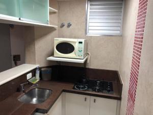 a kitchen with a microwave oven and a sink at Flat mobiliado em Campinas - Ap 124 L Hirondelle in Campinas +22 photos