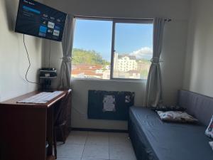 um quarto com um sofá, uma secretária e uma janela em AP Abdon Central Temporada em Joinville