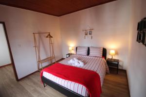 a bedroom with a bed with a red blanket and two lamps at Casas da Biquinha in Sintra