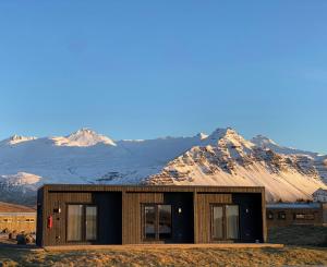 a house with mountains in the background at REY Stays - Small & Cozy Studio in Höfn