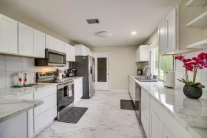 a large white kitchen with white cabinets and appliances at Palm Bay Home with Screened Porch - 8 Mi to Beaches! in Palm Bay