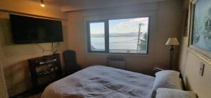 a bedroom with a window and a bed and a television at Departamento Calle España - Vista Lago in San Carlos de Bariloche