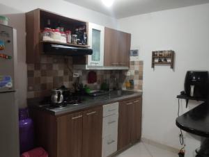 una pequeña cocina con armarios de madera y fregadero en Welcome to Medellin in our home, en Medellín