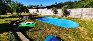 a small swimming pool in a yard with a table and a chair at Rústico Punucapa in Valdivia