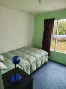 a bedroom with a bed and a blue lamp on a table at Magic Hause Patagonia in Puerto Natales